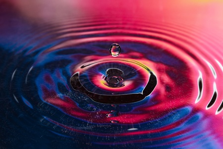 The drop of pure fresh water falls in water with splashes and vialsの写真素材