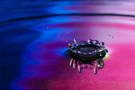 The drop of pure fresh water falls in water with splashes and vials