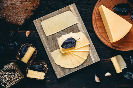 Cheese selection on wooden rustic board. Cheese platter with different cheeses, grapes, nuts, honey and dates on weathered wood background.の写真素材