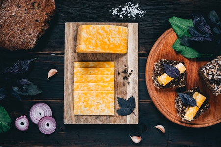 Cheese selection on wooden rustic board. Cheese platter with different cheeses, grapes, nuts, honey and dates on weathered wood background.の写真素材