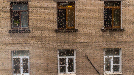 House with windows opposite through the glass with drops. It's raining.