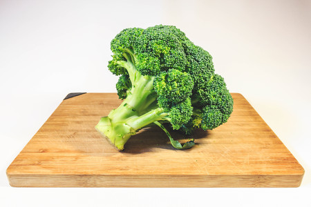 Broccoli cabbage fresh greens on a wooden boardの写真素材