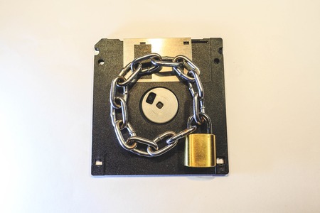 The diskette is protected by a golden lock with a chain.の写真素材
