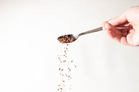 Flax seed handful falls down from the spoon. Whiteの写真素材