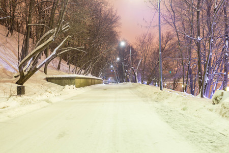 The road in the snow drifts near the river in the park in the eveningの写真素材