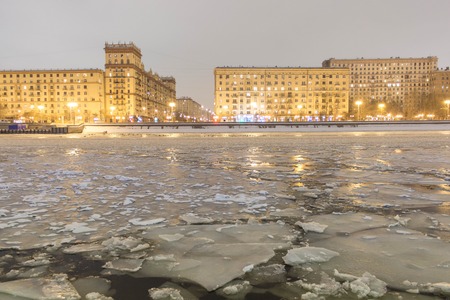 Cracked ice on the river. Spring warming, melting ice. Against the backdrop of urban buildingsの写真素材