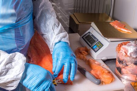 Fish production. Worker cleans fish from bones