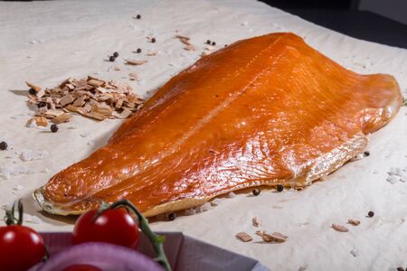 Smoked red fish lies next to smoked sawdust and tomatoes with saltの写真素材