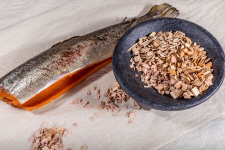 Red hot smoked fish lies next to the sawdust for smoking
