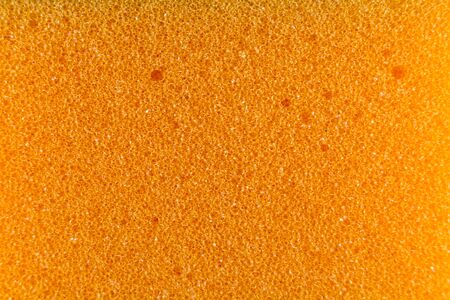 Orange sponge made of microfiber material. Texture, background