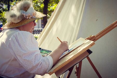 Woman artist paints a watercolor picture on natureのeditorial素材