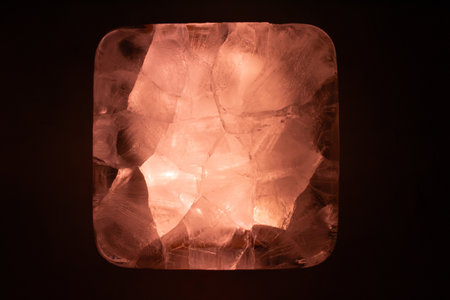 Glowing pink himalayan salt lamp with intricate crystalline structure against dark background