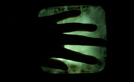 A Mysterious Hand Reaching Through An Illuminated Rectangular Portal In Darkness