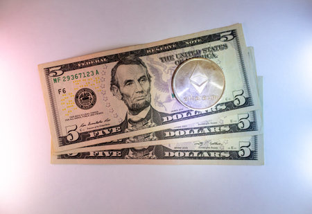 Five dollar bills and ethereum cryptocurrency concept on a dark background