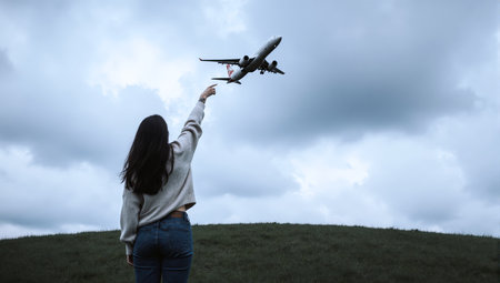 Woman with airplane in the hand on the background of the sky.の素材