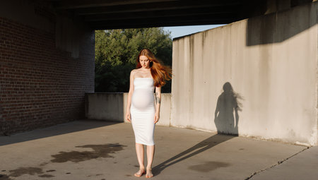 Beautiful young woman in white dress posing in an abandoned building.の素材
