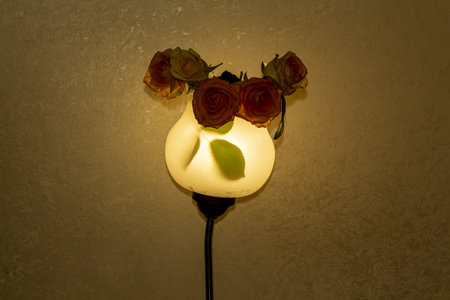 A beautiful still life composition with a wall lamp adorned with delicate roses in a dimly lit roomの写真素材