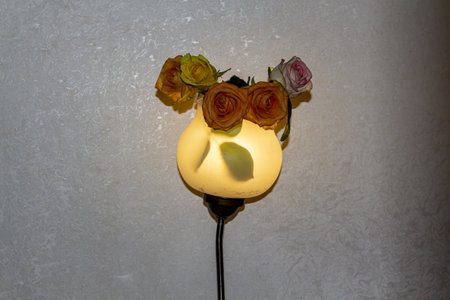 A cozy wall lamp decorated with beautiful roses creating a warm and inviting atmosphere in the room interiorの写真素材