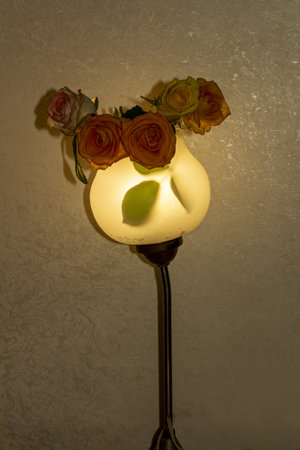 A charming wall lamp decorated with beautiful roses in a cozy interior setting for home decoration and warm illuminationの写真素材