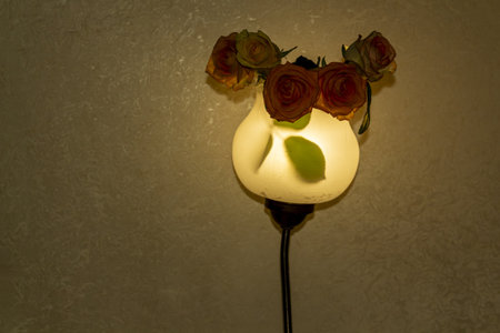 Elegant wall lamp decorated with beautiful brown roses in a cozy room settingの写真素材