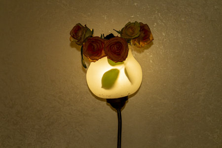 Elegant wall lamp decorated with beautiful roses in a cozy interior settingの写真素材