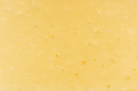 A rich texture of aged swiss cheese with visible holes and golden hue for culinary backgrounds