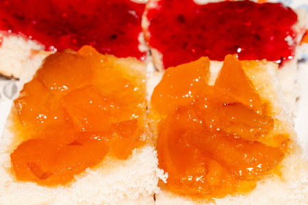 A delicious breakfast with orange marmalade and red jam on white bread slices for healthy eating...