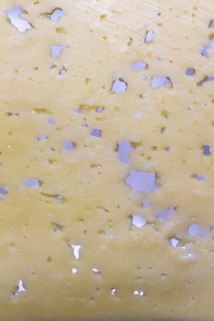 A detailed texture of swiss cheese with large holes perfect for food backgrounds and culinary...