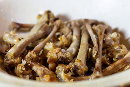 A pile of leftover chicken bones in a white bowl after enjoying tasty meal delicious food concept