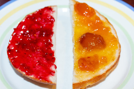 Delicious homemade breakfast with raspberry jam and apricot preserve on toast halves