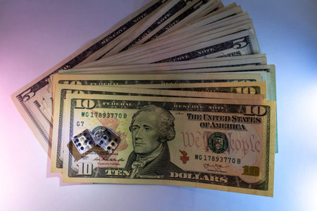 A stack of ten dollar bills with dice on top for a gambling conceptのeditorial素材