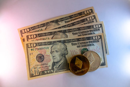 Ten dollar bills and ethereum cryptocurrency coin on white backgroundのeditorial素材
