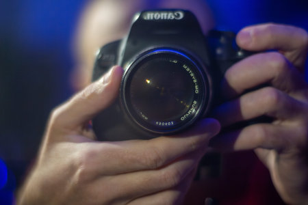 A person holding a digital slr camera focusing on an object in low light conditions at night