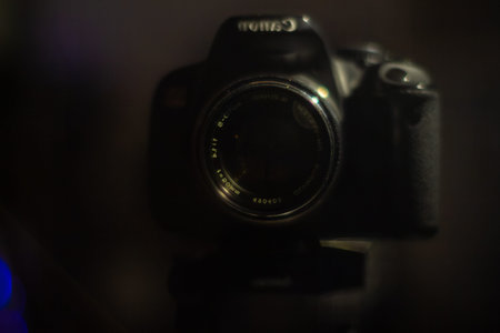 Professional dslr camera on table in dark room with colorful lights background for advertising and...