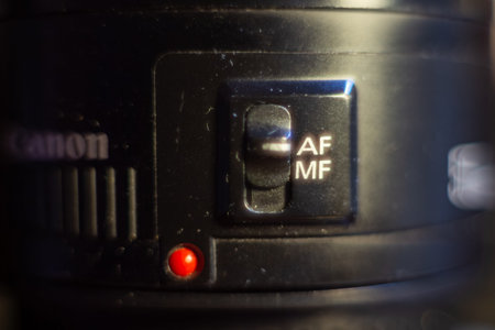 A detailed view of canon lens focusing switch with red indicator light for professional photography...
