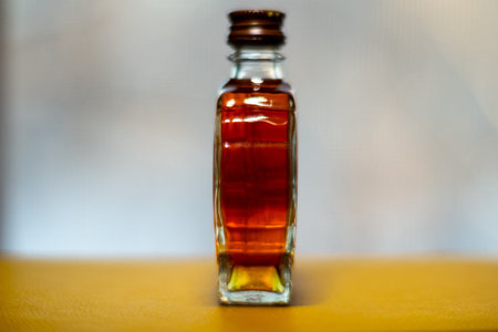 A small bottle filled with amber liquid for perfume or essential oil on wooden surface