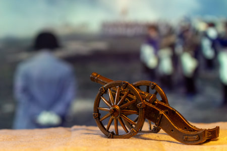 A miniature cannon resting on table with blurred historical scene in background