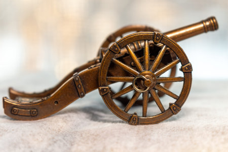 A beautiful antique miniature cannon on a light textured surface for historical concepts and...