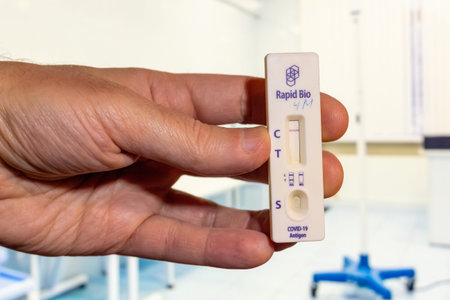 A hand holding covid-19 rapid antigen test kit showing negative result in medical clinic