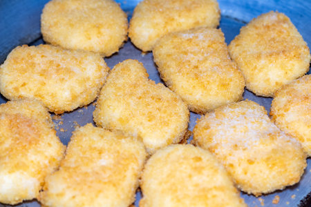 A delicious heap of golden fried fish nuggets on blue plate ready to serve appetizing snackの写真素材