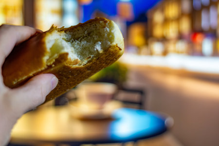 A delicious bite of a soft bun with fluffy crumb in hand against the backdrop of a blurred city...