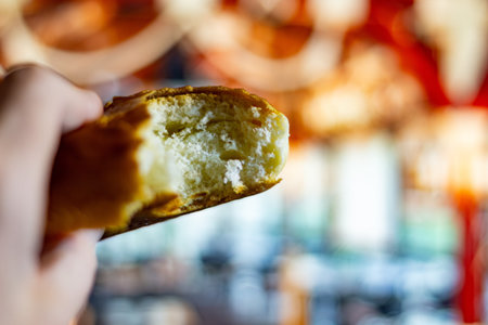 A delicious bite of freshly baked pretzel with salty crust and soft interior held in handの写真素材