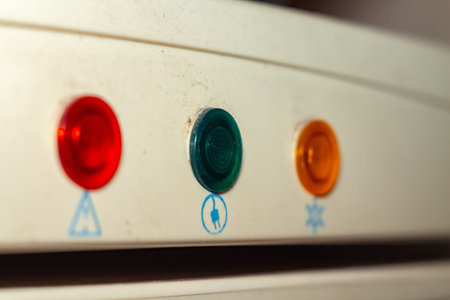 A row of three illuminated warning indicator lights on beige equipment panel
