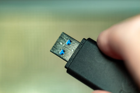 A modern black usb flash drive held by a hand in blurred background for data transfer technology...