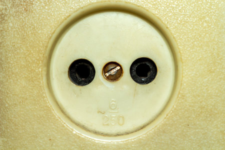 A vintage european electrical socket with three holes on a beige surface background for design...