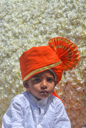 Pune, India - September 4, 2017: Vertical portrait of a small kid wearing white kurta and orange...