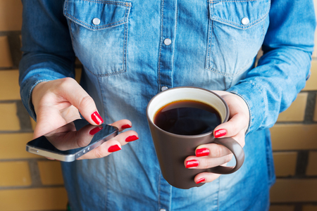 woman with cup of coffee using phoneの写真素材