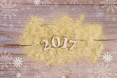 number 2017 on wooden background with golden glitter