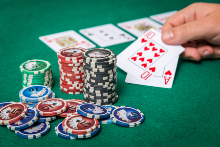 chips and cards for poker in hand on green table