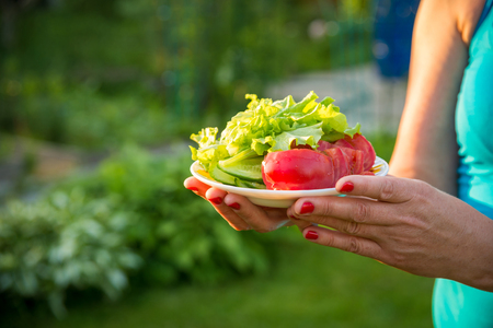 woman holding a plate with fresh vegetablesの写真素材